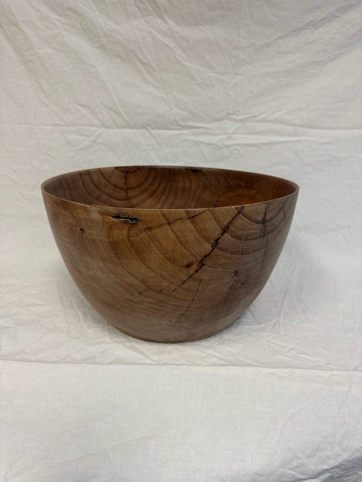 Hand-turned bowl in warm brown wood with a natural bark-inclusion mark