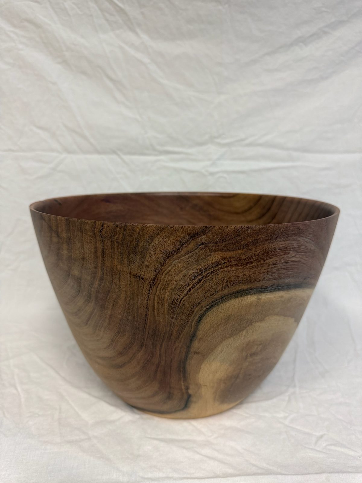 Hand-turned bowl in deep reddish-brown wood with a pale sapwood patch