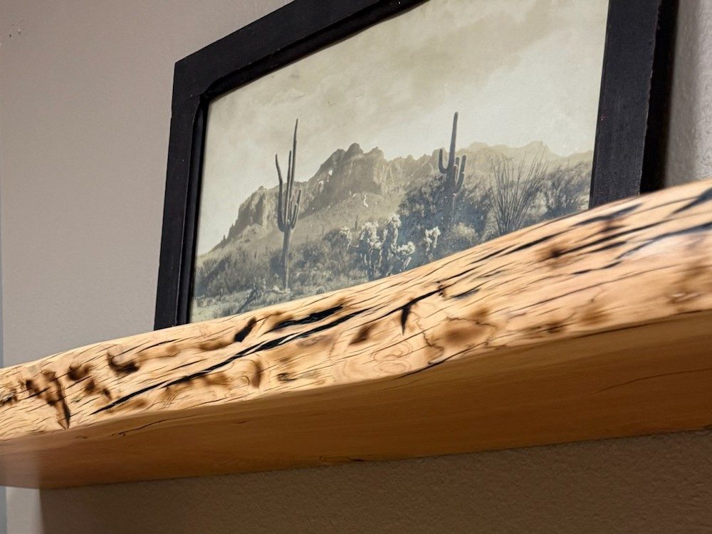 Alligator juniper live-edge floating shelf mounted on a studio wall