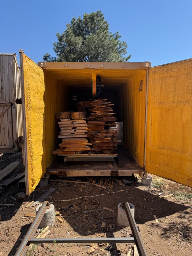 The drying kiln, a shipping container with its doors open and slabs stacked inside
