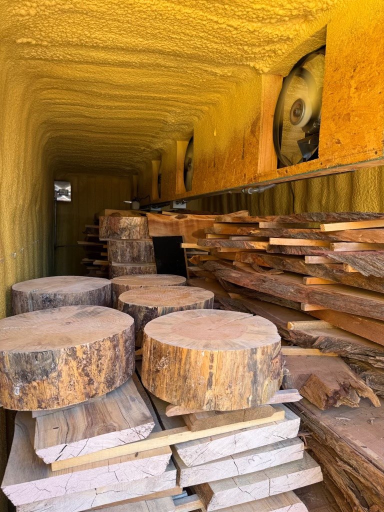 Inside the kiln: round slab cookies and live-edge slabs stacked to dry